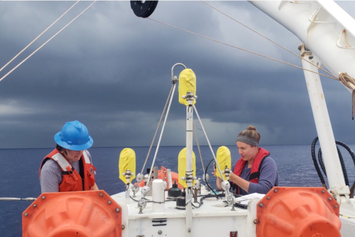 Two scientists working with equipment at sea.